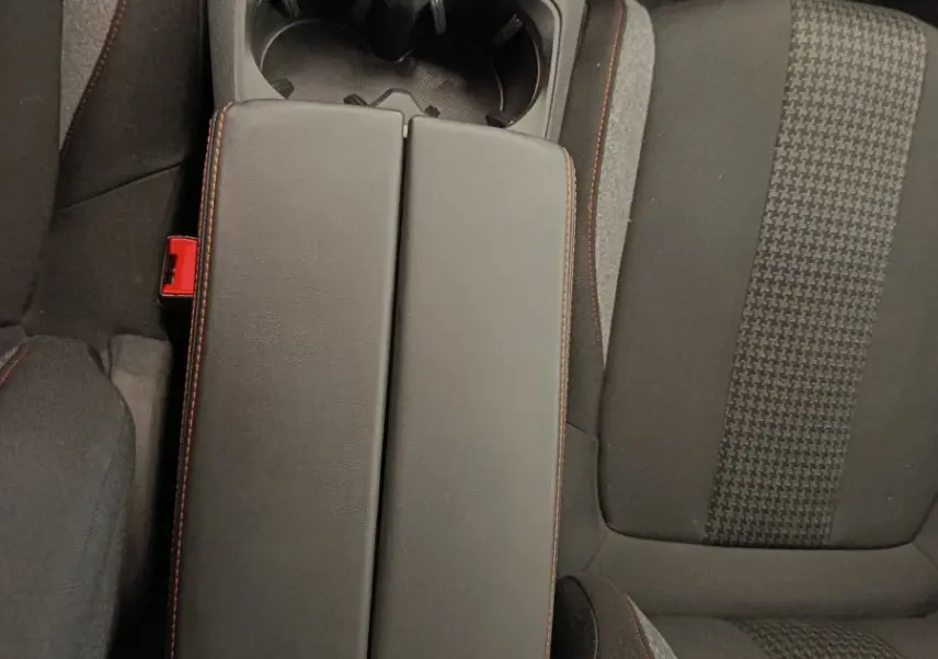 Vue plongeante sur la console centrale et les sièges avant en tissu noir avec surpiqûres rouges du Peugeot 5008 gris foncé.