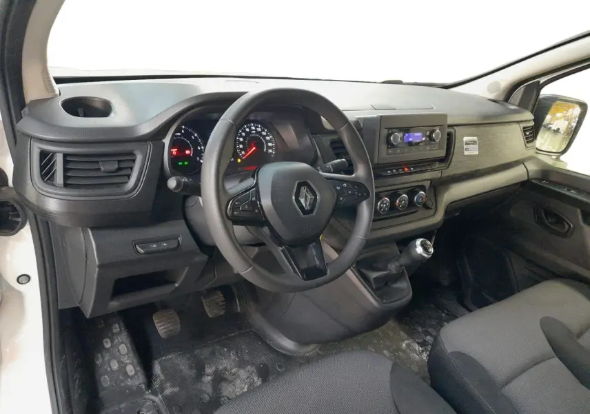 Vue intérieure côté conducteur du Renault Trafic Fourgon 2024, tableau de bord noir avec volant multifonction et levier de vitesse manuel.
