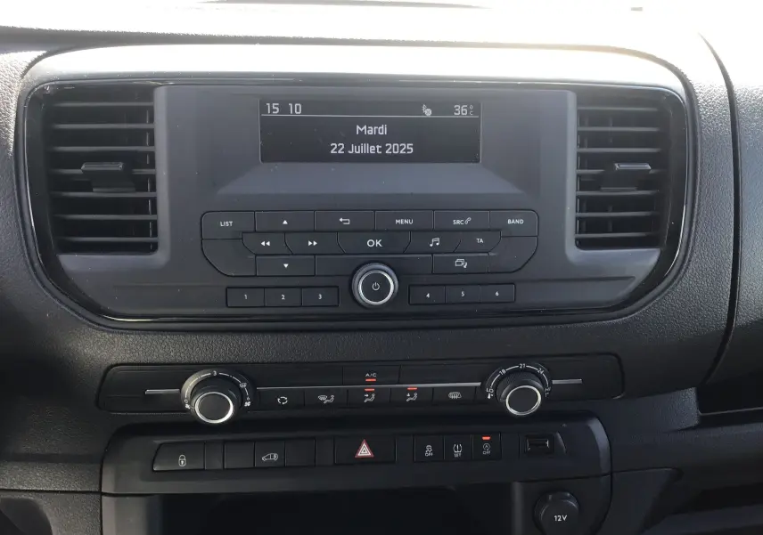 Tableau de bord central de l'Opel Vivaro blanc 2023, avec écran multifonction et commandes de climatisation visibles.