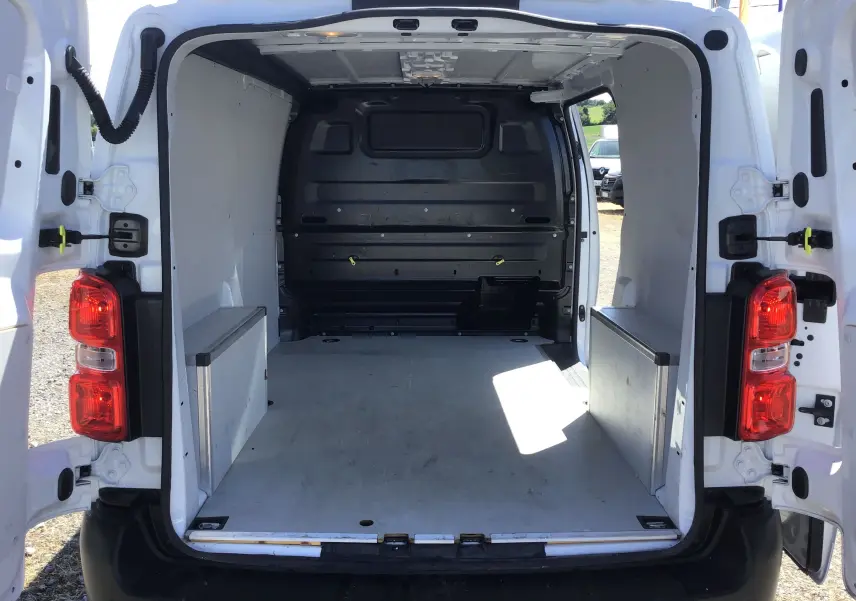 Vue arrière ouverte du fourgon blanc Opel Vivaro M 1.5 BlueHDi 120 2023, montrant l'espace de chargement vide et aménagé.