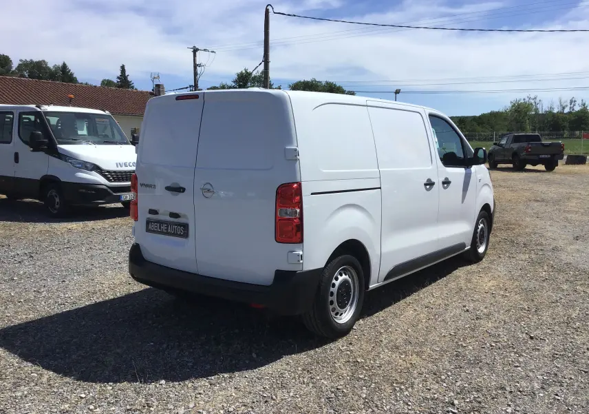 Vue 3/4 arrière droite d'un utilitaire Opel Vivaro blanc 2023 avec portes arrière pleines et jantes acier noires.