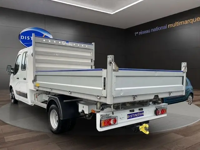 Vue 3/4 arrière droite d’un Renault Master blanc double cabine avec benne et coffre, équipé d’un attelage jaune visible.