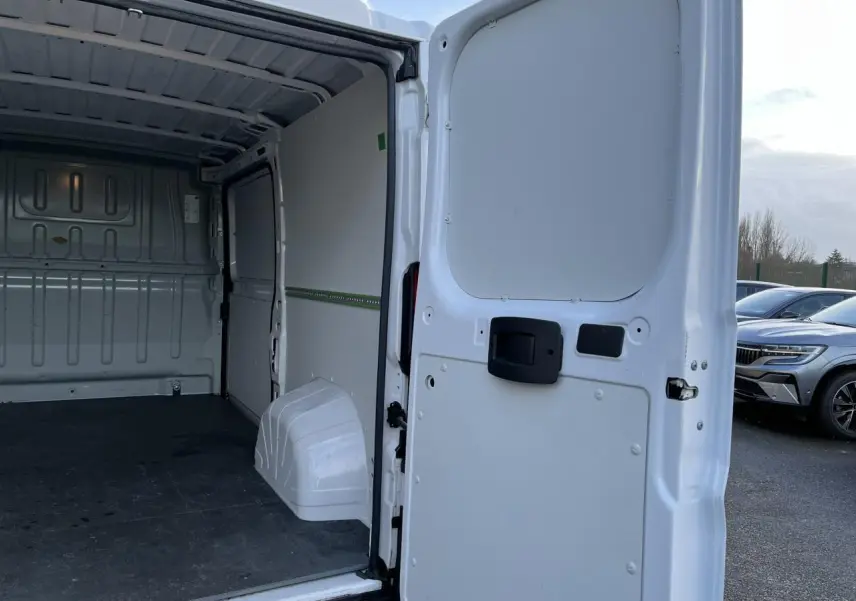 Vue arrière ouverte du fourgon blanc Opel Movano 2024, montrant l’intérieur vide avec plancher et habillage bois.