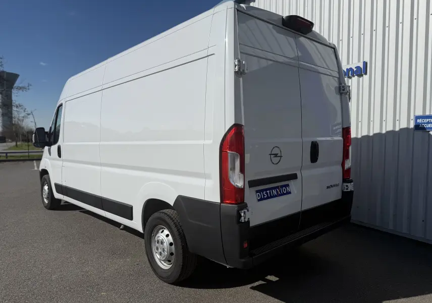 Vue intérieure côté conducteur de l’Opel Movano Fourgon blanc 2023, tableau de bord avec écran tactile et levier de vitesses manuel.