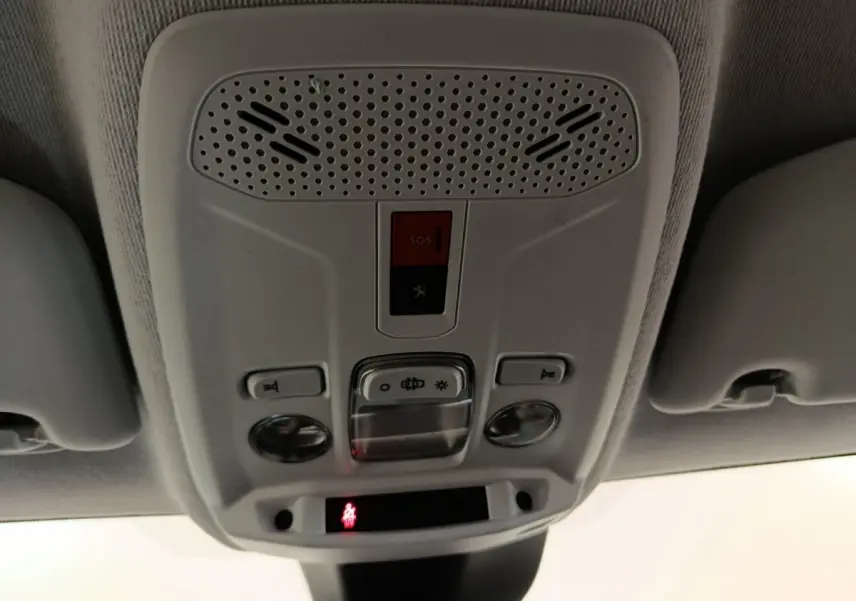 Vue intérieure en gros plan du plafonnier gris avec boutons SOS et éclairage de la Peugeot 208 électrique blanche.