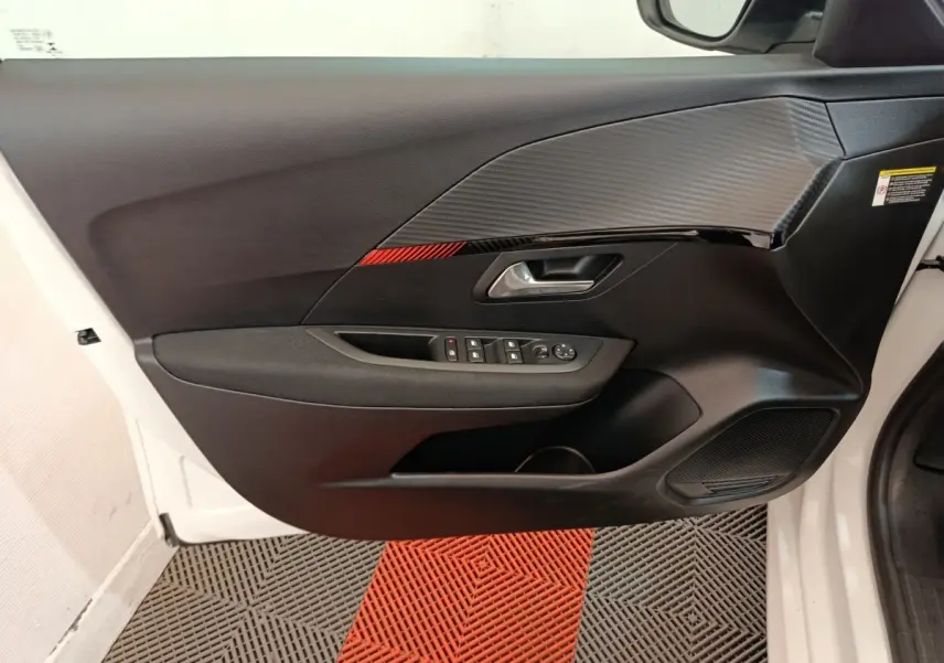 Vue intérieure de la porte avant gauche blanche du Peugeot 208 électrique avec insert décoratif noir et rouge.