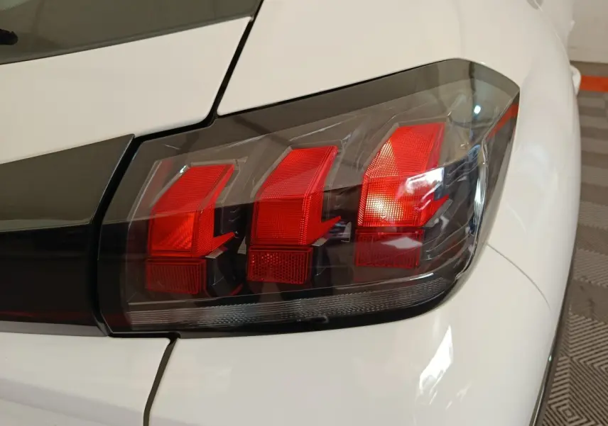 Gros plan sur le feu arrière droit rouge et noir de la Peugeot 208 électrique blanche, version Active Business R.