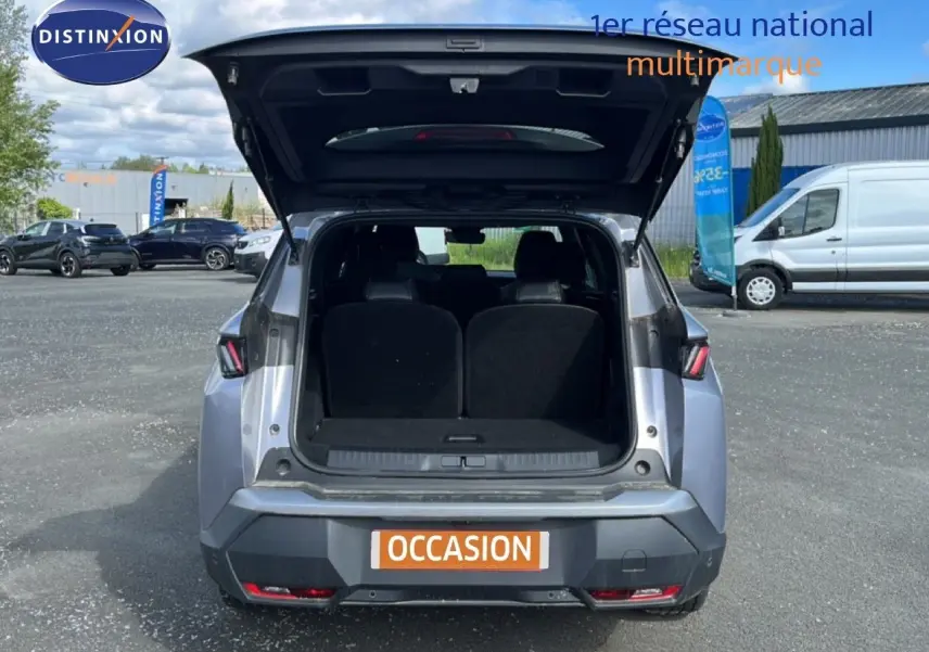 Vue arrière d’un Peugeot 5008 gris Artense métal 2025 avec coffre ouvert sur parking extérieur.