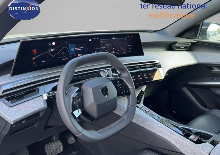 Vue intérieure côté conducteur du Peugeot 5008 Hybrid 2025, mettant en valeur le tableau de bord numérique et le volant cuir gris.