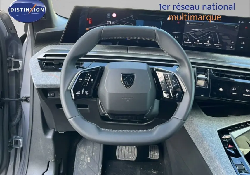 Vue intérieure centrée sur le volant gris cuir du Peugeot 5008 Hybrid 2025 avec tableau de bord numérique et écran tactile.