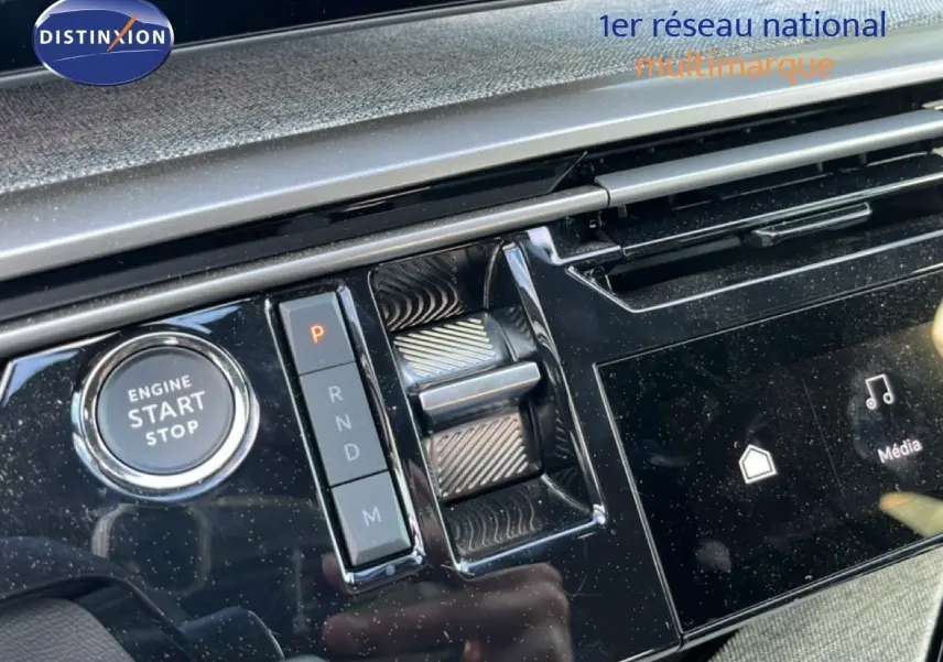 Gros plan sur la console centrale noire brillante du Peugeot 5008 gris, avec bouton start/stop et commande de boîte auto.