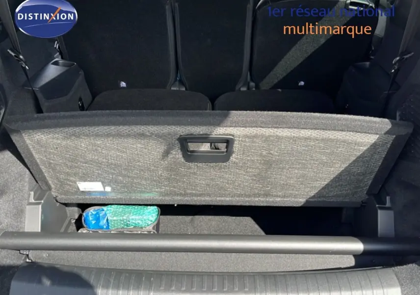 Vue plongeante sur le coffre ouvert d’un Peugeot 5008 gris Artense, montrant le compartiment de rangement sous la tablette.