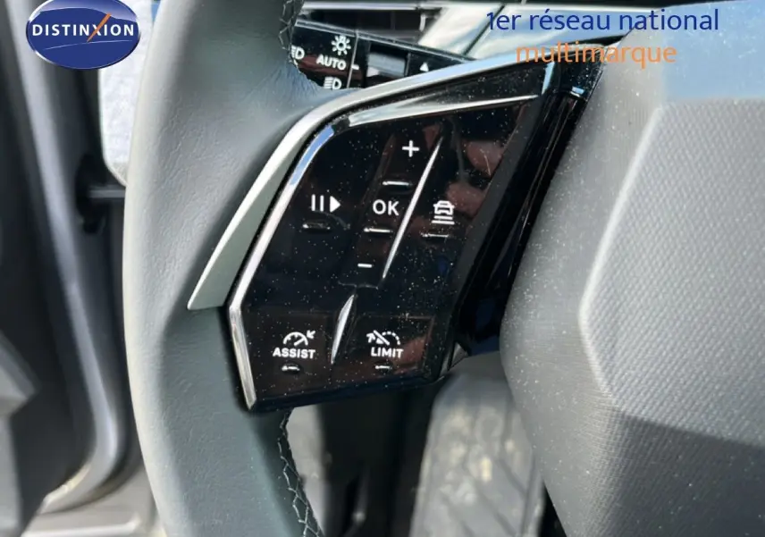 Gros plan sur les commandes gauche du volant du Peugeot 5008 gris Artense, boutons de régulateur et assistant visibles.