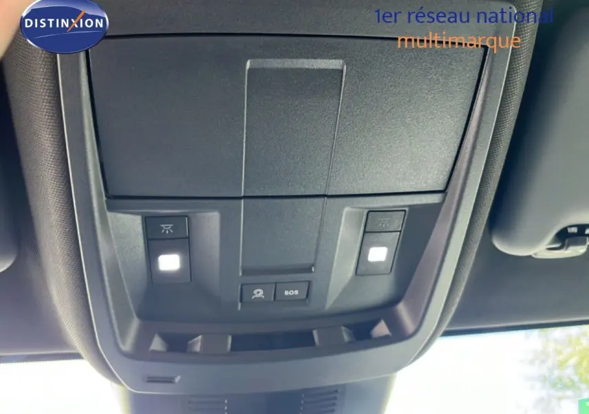 Vue en contre-plongée du panneau de commandes au plafond intérieur du Peugeot 5008 gris Artense métal, avec boutons d’éclairage et SOS.