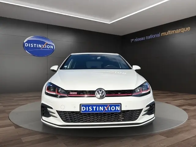 Vue frontale d'une Volkswagen Golf GTI Performance blanche, avec calandre noire et détails rouges distinctifs.
