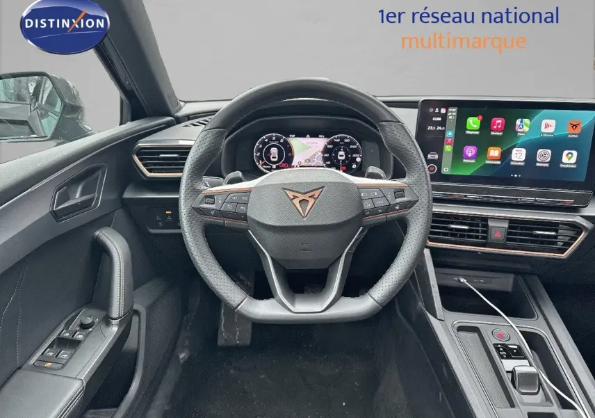 Intérieur du CUPRA LEON ST 2024 en noir, vue centrée sur le volant multifonction et l'écran tactile moderne.
