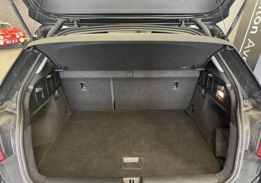 Coffre ouvert vu de l'arrière d'un Audi Q2 noir 2022, intérieur spacieux et tapis de sol sombre.