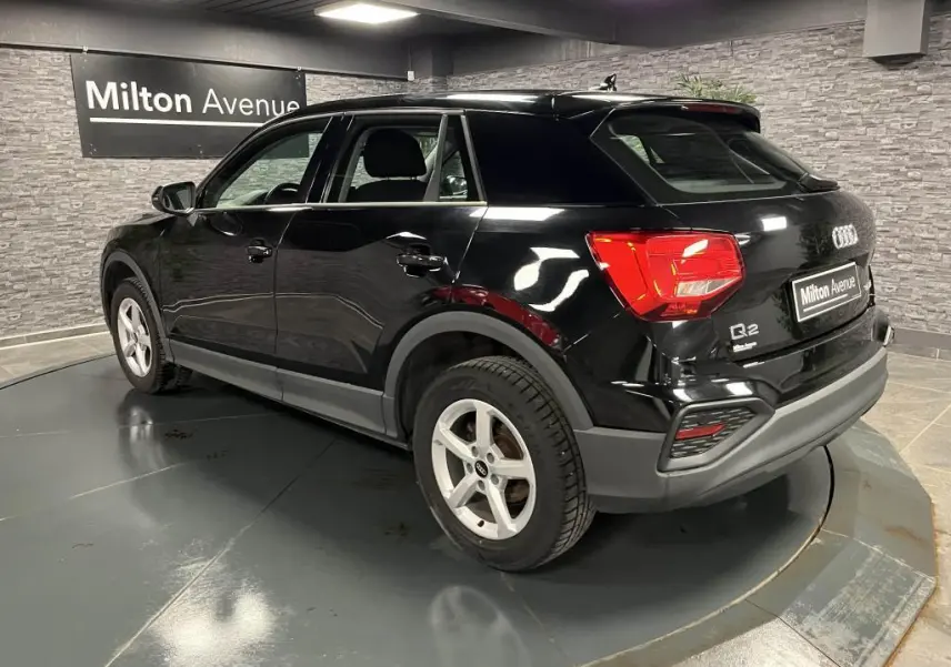 Audi Q2 noir brillant vue 3/4 arrière droit, avec jantes aluminium 5 branches et feux arrière LED visibles.