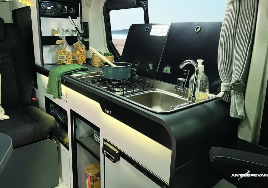 Cuisine équipée avec évier et plaque gaz dans l'aménagement Antilope Van du Renault Trafic blanc, vue intérieure côté droit.