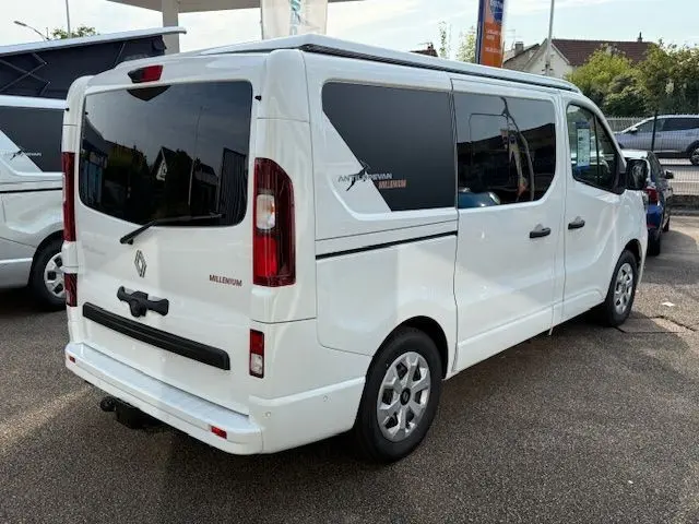 Vue 3/4 arrière droite du Renault Trafic Fourgon blanc glacier avec vitres arrière teintées et badges Antilope Van Millenium.