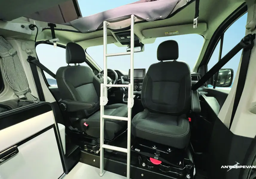 Intérieur du Renault Trafic Fourgon blanc glacier, vue avant sur sièges pivotants noirs et échelle d'accès au toit relevable.