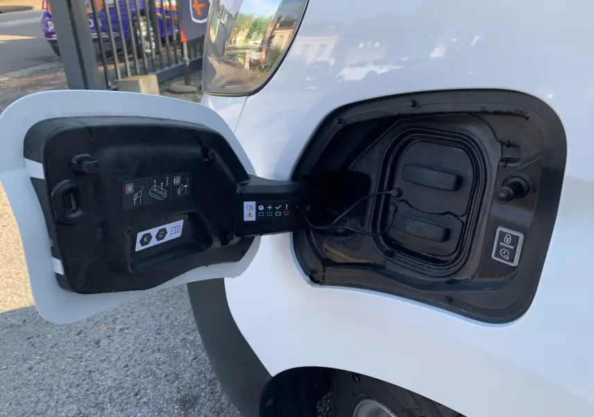 Prise de recharge électrique ouverte côté avant droit d'un FIAT Scudo Combi blanc 2022, détail du câble et du bouchon.