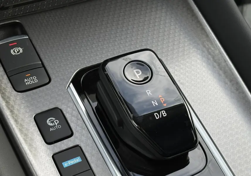 Gros plan sur la commande de boîte automatique noire et les boutons de frein à main et e-Pedal dans le console centrale du Nissan Qashqai blanc nacré.