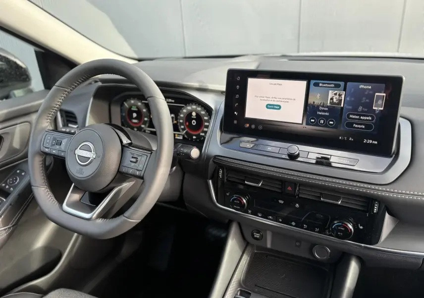 Vue intérieure côté conducteur du Nissan Qashqai blanc nacré 2025, avec tableau de bord numérique et écran tactile central.