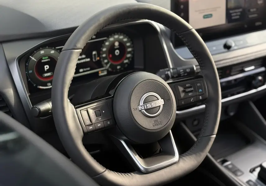 Vue rapprochée du volant cuir noir et du tableau de bord numérique du Nissan Qashqai blanc nacré 2025.