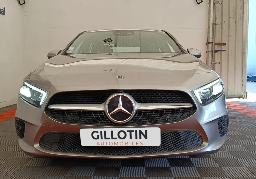 Vue frontale d'une Mercedes Classe A 180 Business Line gris clair avec phares LED allumés dans un garage.