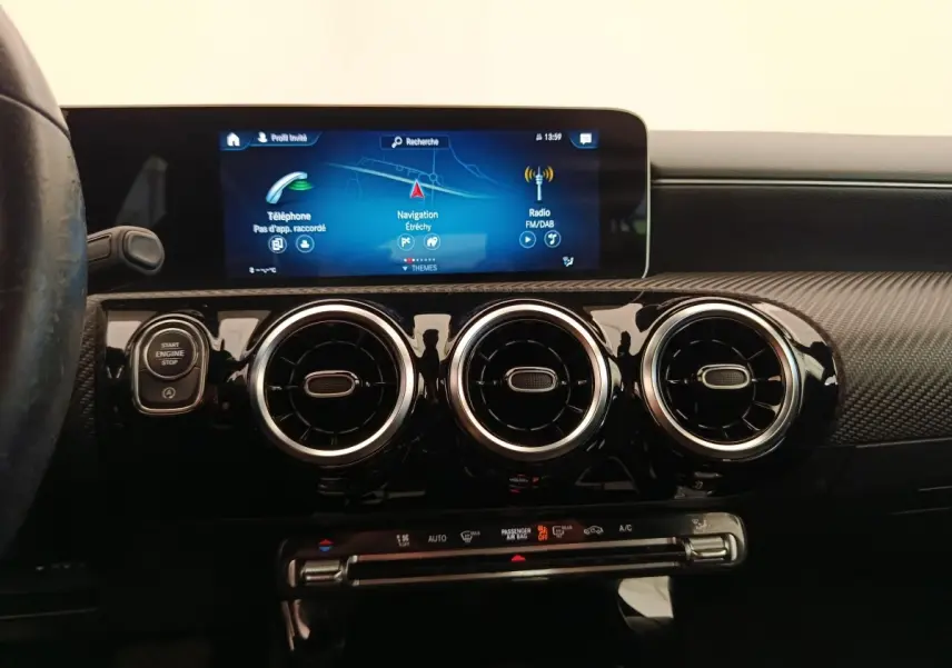 Vue intérieure centrée sur la console de la Mercedes Classe A 180 Business Line 2020, avec écran tactile et aérateurs ronds noirs.