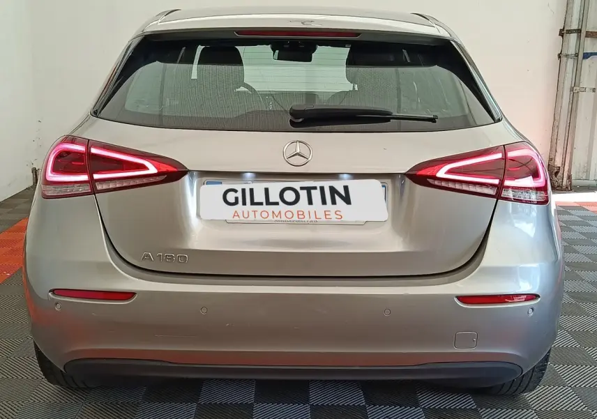 Vue arrière d'une Mercedes Classe A 180 Business Line gris clair avec feux LED et logo Mercedes visible.