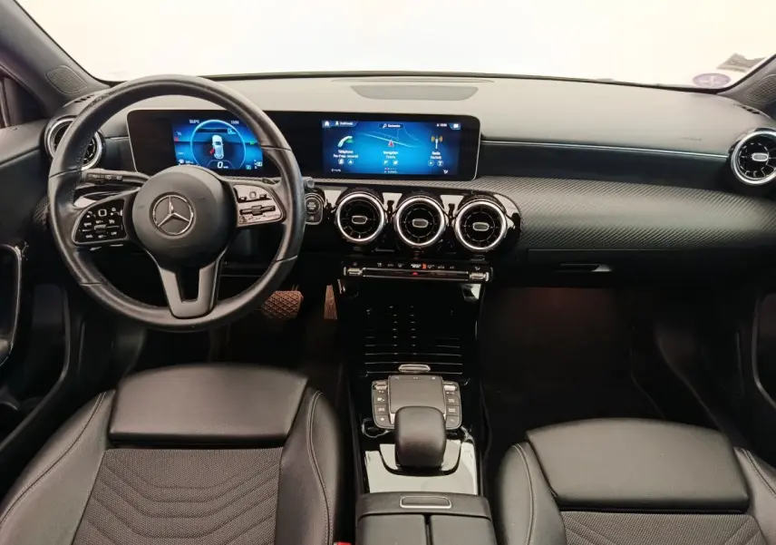Vue intérieure avant de la Mercedes Classe A 180 Business Line 2020, tableau de bord noir avec écran tactile et volant cuir multifonctions.