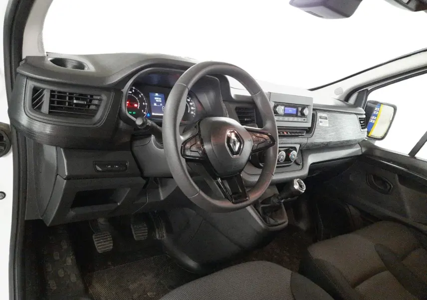 Vue intérieure côté conducteur du Renault Trafic Fourgon 2024, tableau de bord noir avec volant multifonction et levier de vitesse manuel.