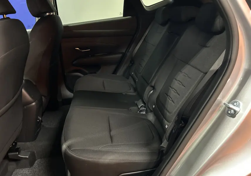 Vue intérieure arrière côté droit du Hyundai Tucson 2025 hybride en tissu noir avec porte ouverte et détails des sièges arrière.