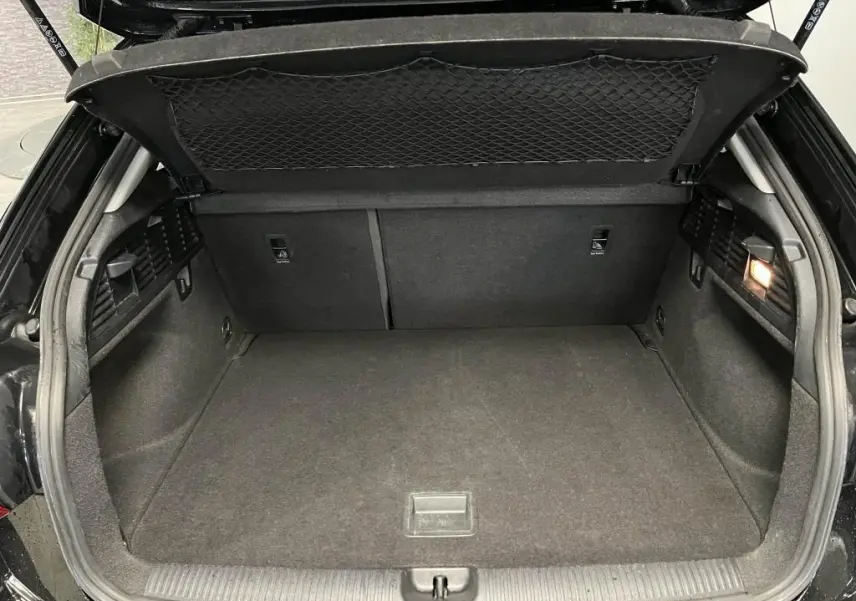Coffre ouvert de l'Audi Q2 noir 2022, montrant un espace de chargement propre avec filet de rangement sous le hayon.