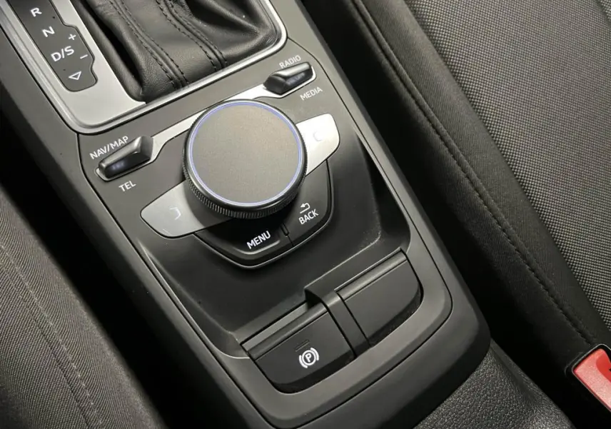 Gros plan sur la console centrale noire de l'Audi Q2 2022 avec molette de commande et levier de boîte automatique.