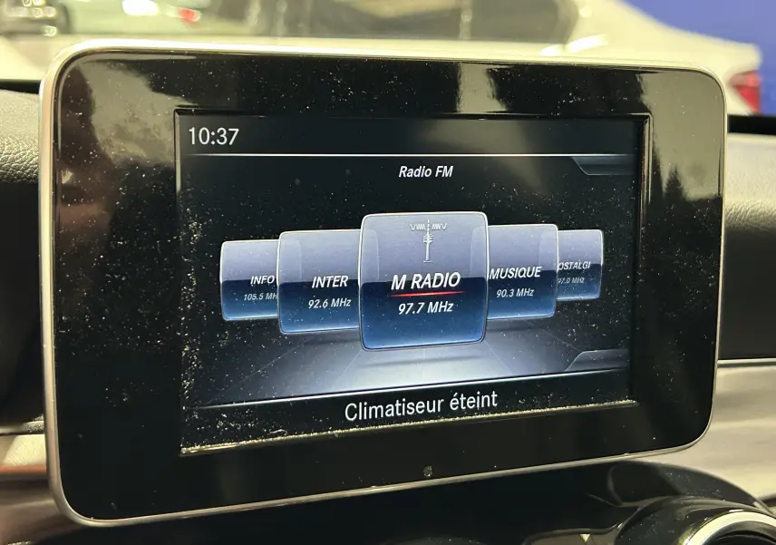 Écran central du système multimédia d'une Mercedes Classe C 200d bleu, affichant la radio FM et l'heure 10:37.