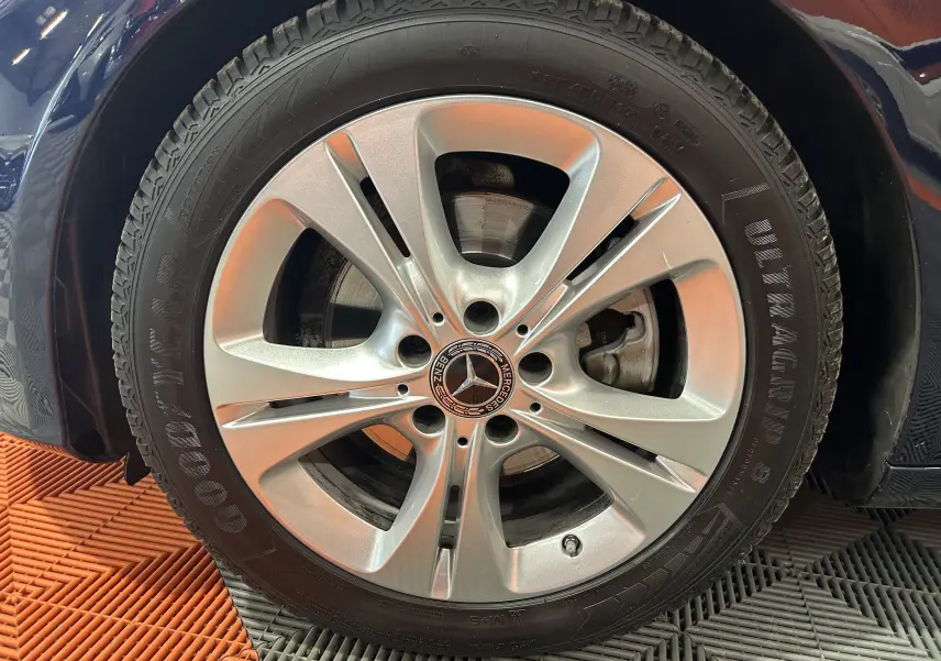 Gros plan sur la jante argentée et le pneu Goodyear d'une Mercedes Classe C 200d bleu, vue côté avant gauche.