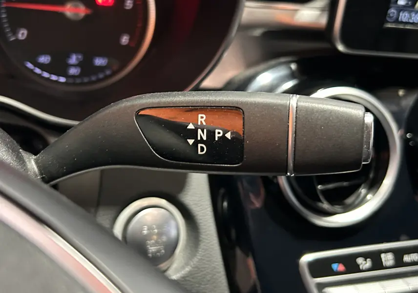 Le levier de boîte automatique avec les positions R, N, P, D dans l'habitacle d'une Mercedes Classe C bleue de 2018.