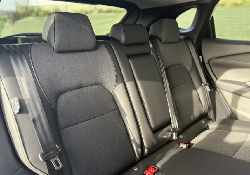 Vue intérieure des sièges arrière noirs du Nissan Qashqai III e-Power 2025 avec ceintures et appuie-têtes visibles.