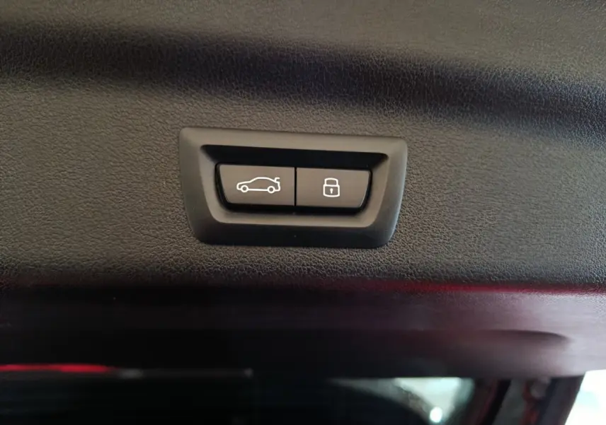 Gros plan sur les boutons d'ouverture et de verrouillage du coffre noir intérieur du BMW X1 xDrive23i M Sport 2023.