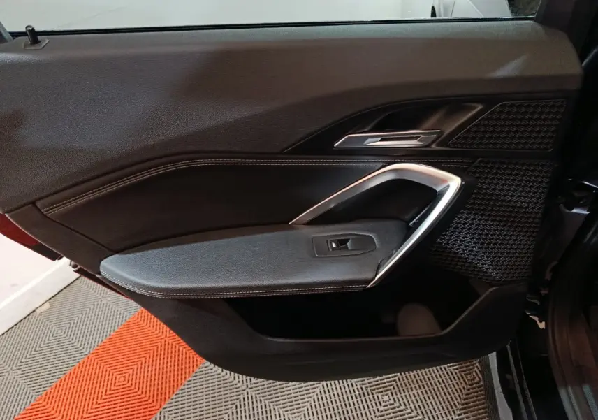 Vue intérieure côté gauche de la porte avant noire du BMW X1 xDrive23i M Sport avec insert argenté et tissu texturé.