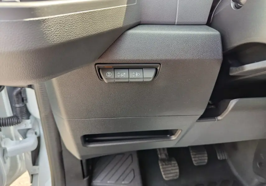 Détail intérieur côté gauche du tableau de bord du Renault Master blanc, avec commandes d’éclairage et pédales visibles.