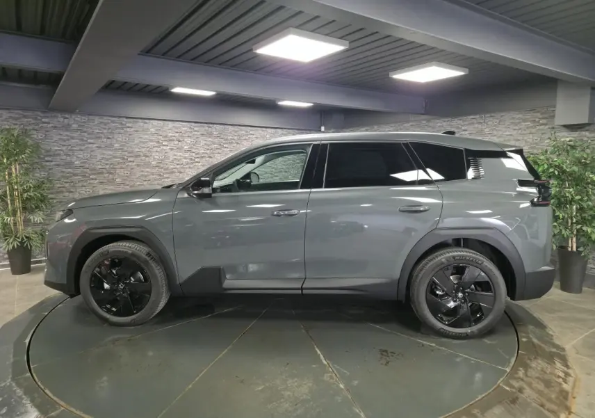 Vue de profil côté gauche d'un Citroën C5 Aircross 2026 vert métallisé avec jantes alliage noires en showroom.