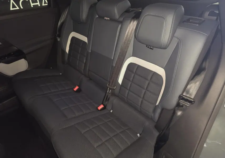 Vue intérieure sur la banquette arrière noire et grise du Citroën C5 Aircross 1.2i Hybride 2026 avec ceintures visibles.