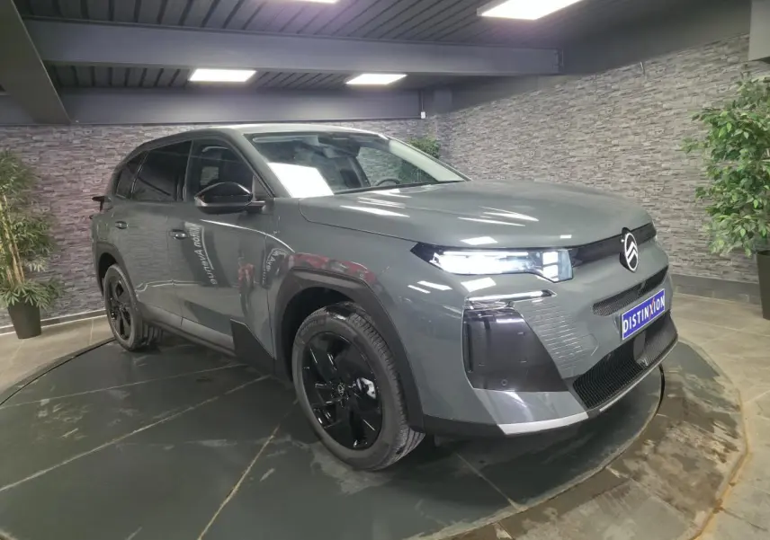 Citroën C5 Aircross gris 3/4 avant droit avec jantes noires et calandre noire brillante en intérieur showroom.