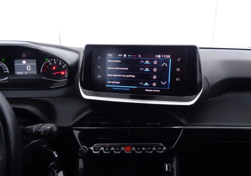 Intérieur du tableau de bord de la Peugeot 208 2020, avec écran tactile central et commandes en rangée sous l'écran.