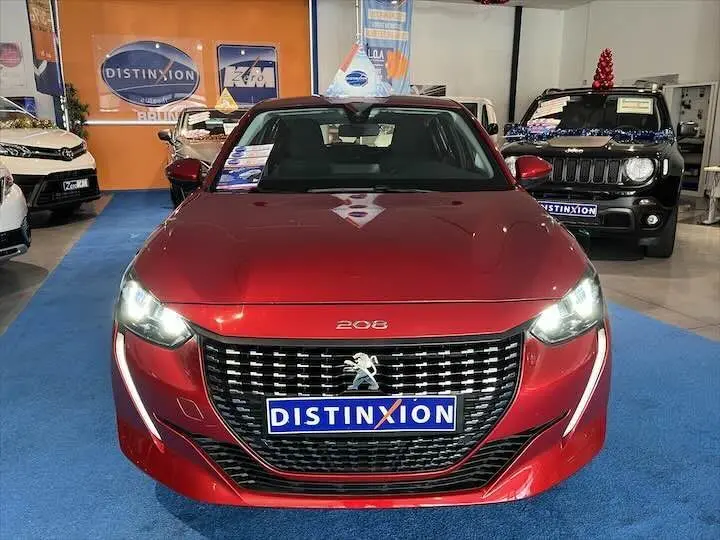 Vue frontale d'une Peugeot 208 rouge Elixir Metal avec calandre noire et logo lion, en showroom Distinxion.