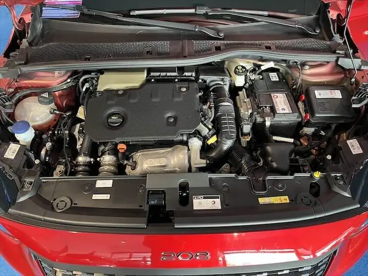 Moteur diesel Peugeot 208 rouge Elixir vu de dessus avec capot ouvert, montrant le compartiment moteur complet.